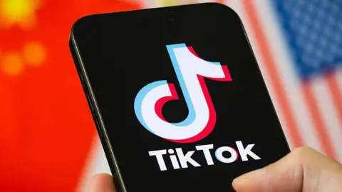 Getty Images Smartphone displays the logo of TikTok with the national flags of China and the United States in the background.